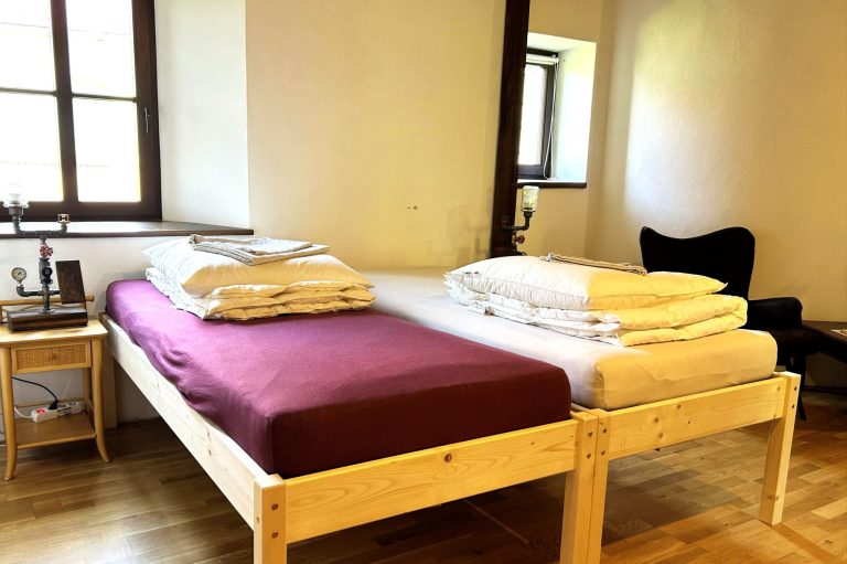 Ferienwohnungen Rittergut Leppersdorf Maritimes Doppelbett mit Nachtkonsolen in der Kemenate Penzlin, umgeben von hellem Holzfußboden.