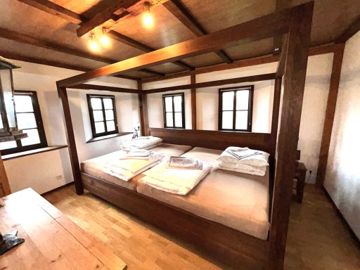 Ein helles Schlafzimmer mit einem Doppelbett und großen Fenstern.