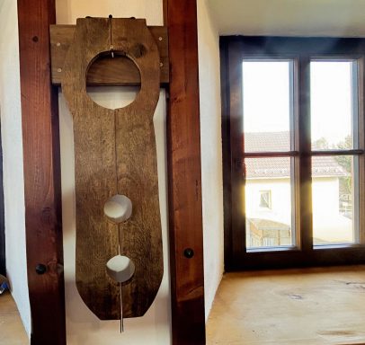 Holzpult mit drei Löchern, an einer Wand in einem hellen Raum mit Fenster.